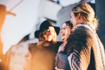 Three women smiling and laughing while facing away from the camera. image link to story