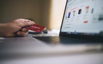 hand at computer keyboard holding credit card for online purchase image link to story