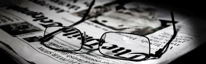 a pair of eyeglasses set on top of a folded newspaper