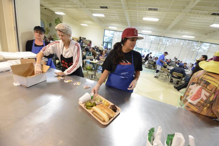 People working in a kitchen preparing food with paper bags.