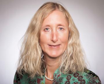 Woman in a green patterned blazer, neutral background.