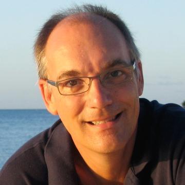 A person smiling with a body of water in the background.