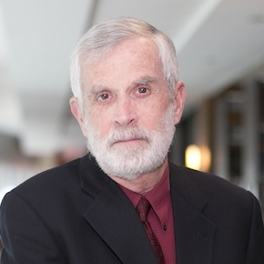 A man in a suit with a blurred background.