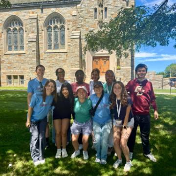 AMDG Fellows 2025-26 students and leader Valerie Sarma in front of chapel Boston College
