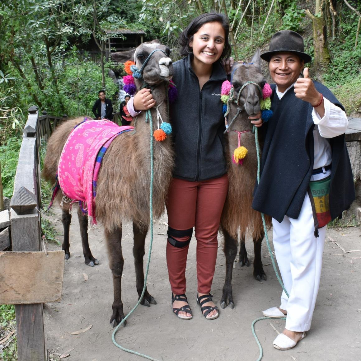 Two people smiling with donkeys in a forest. 