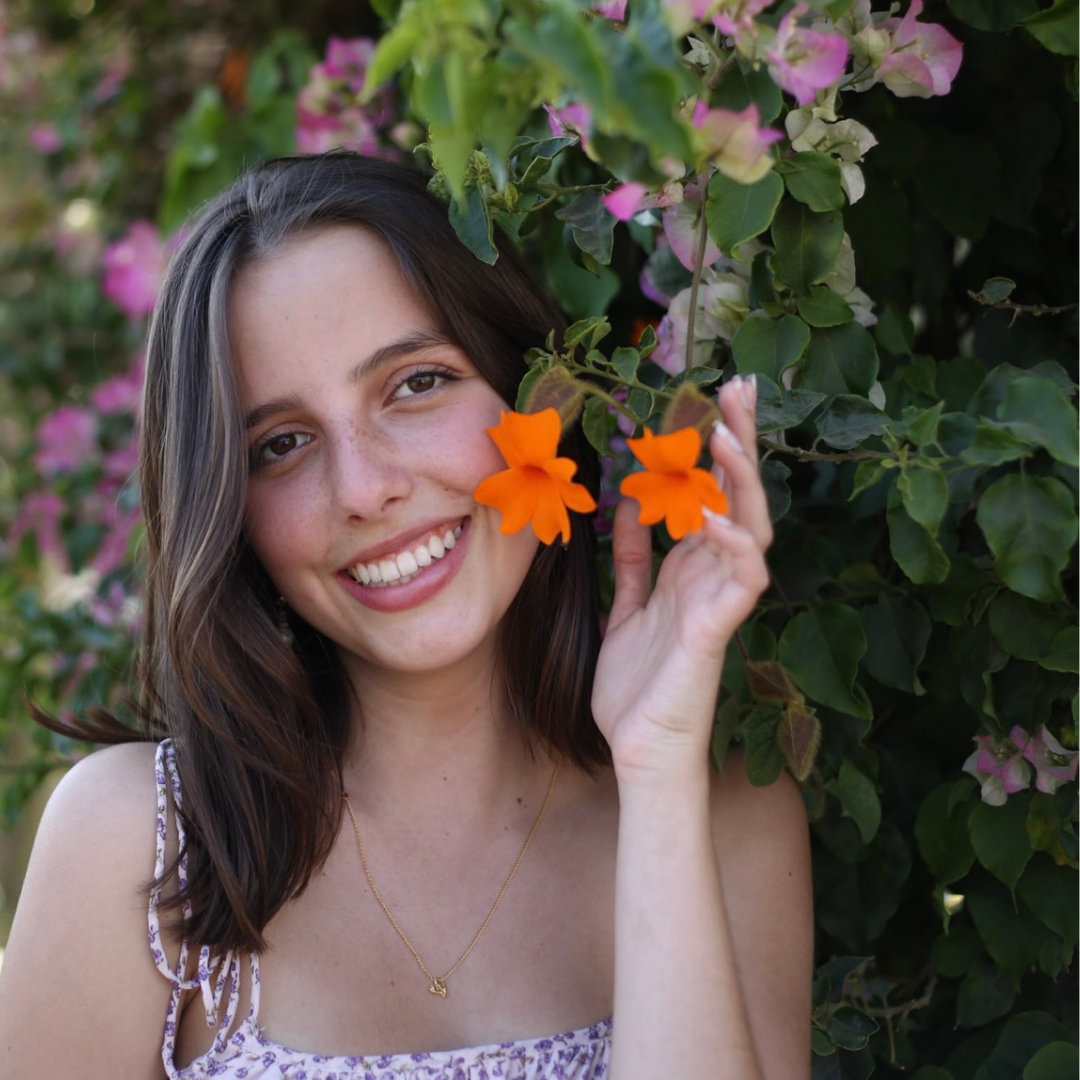 A student standing next to a flowering tree 