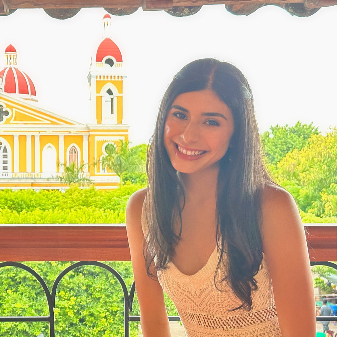 A student in front of trees and a church building 