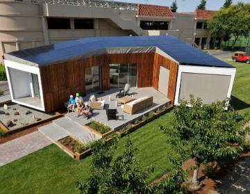 Modern wooden house with solar panels and a large patio. image link to story