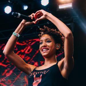 Willow Smith making a heart shape with her hands on stage.