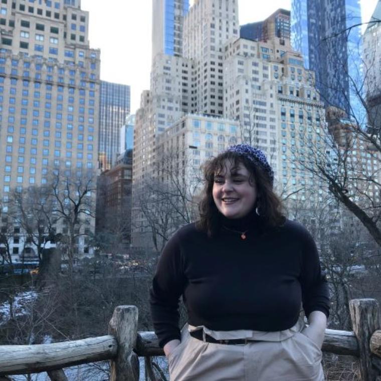 A person smiling with skyscrapers in the background.