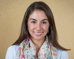 A person smiling, wearing a colorful scarf and light-colored shirt.