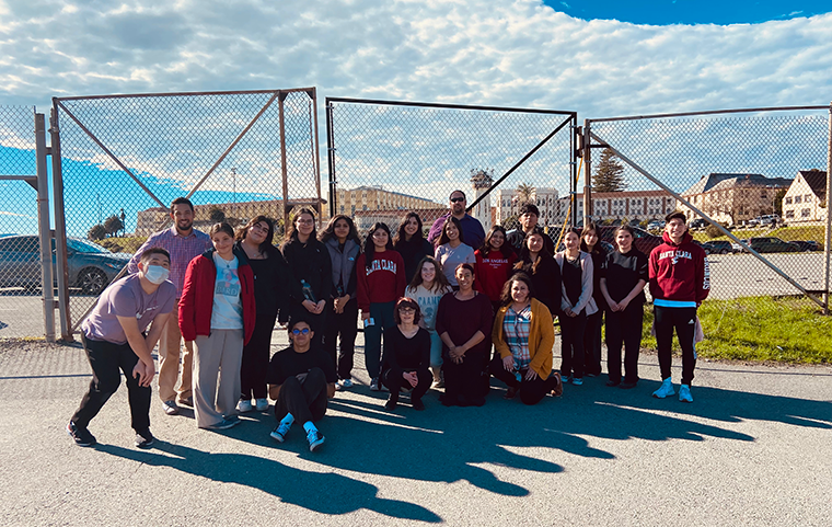 A group of Santa Clara students and faculty stand in front of prison gates.