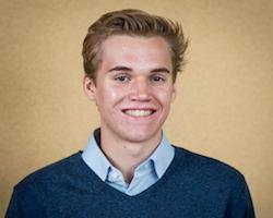 Young adult in a blue sweater and collared shirt smiling.