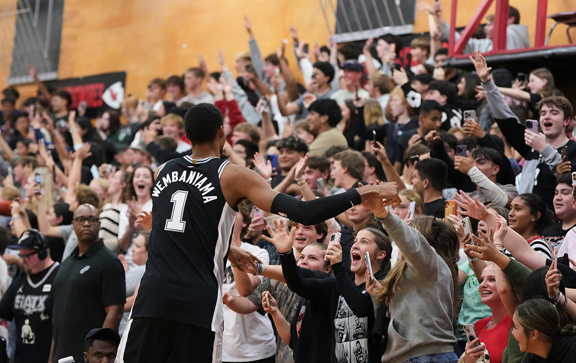 Spurs star player Victor Wembanyama greets an enthusiastic crowd of fans during a court flood.