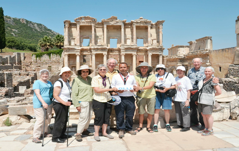 A group of people posing in front of ancient ruins. image link to story