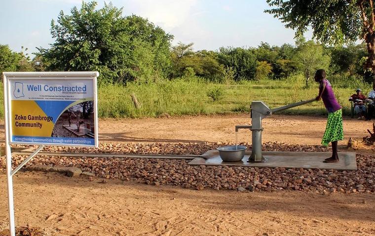 Photo of a Ghanaian woman using a Well Constructed hand pump well.