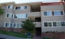 Three-story beige apartment building with balconies and windows labeled 