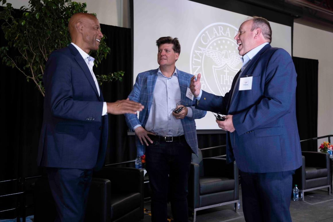 Three people in suits conversing at a formal event or conference.