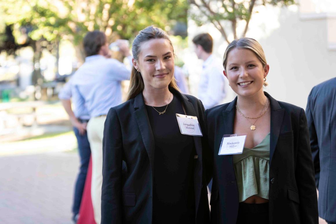 Two women standing with name tags at an outdoor event.