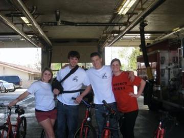Four people standing in a garage with bicycles.