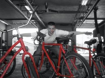 A person in a garage surrounded by red bicycles.