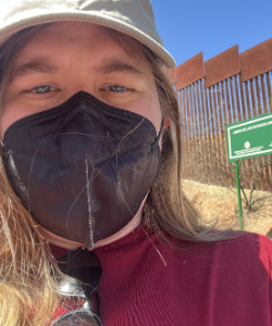 Person wearing a mask with a desert and fence in the background.