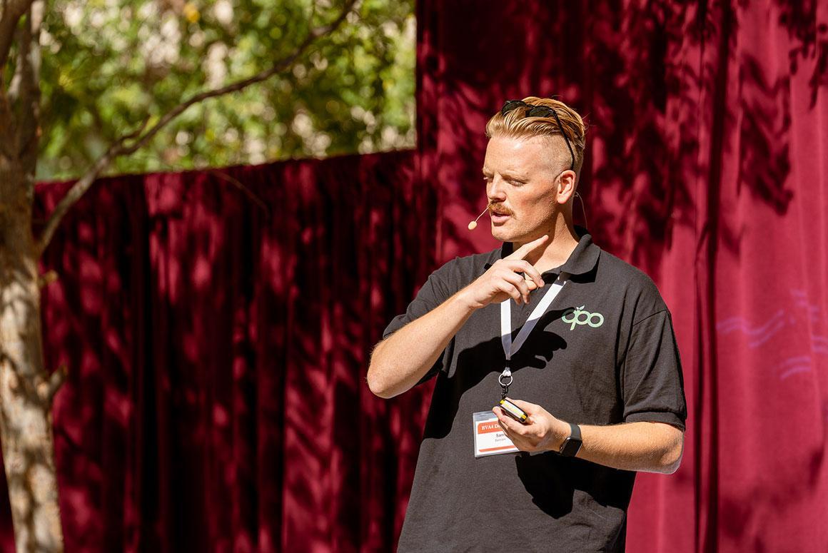 Person speaking at an outdoor event with a microphone.