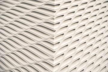 Corner of a white building with a repetitive, perforated pattern.