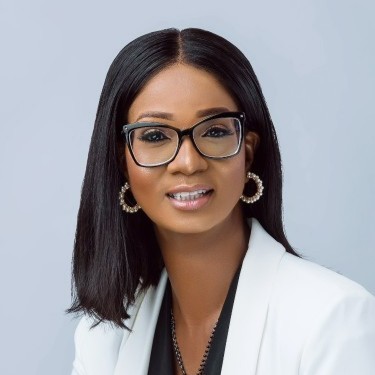 A person wearing glasses and a white blazer, smiling.