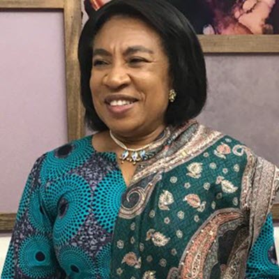 A woman smiling, wearing a colorful patterned scarf.