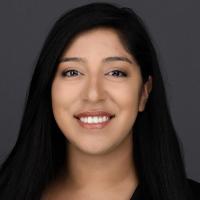 A person smiling with a grey background.