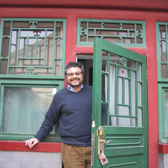 A person standing in front of a colorful building with an open door.