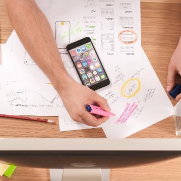 person writing on white paper, scrabble tiles and smartphone