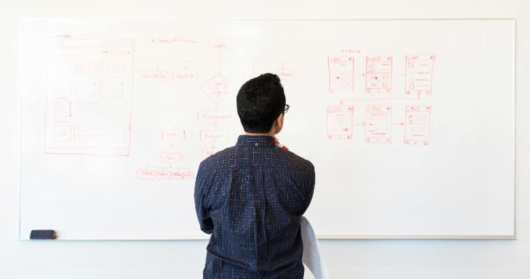 Professional looking at options on a whiteboard image link to article