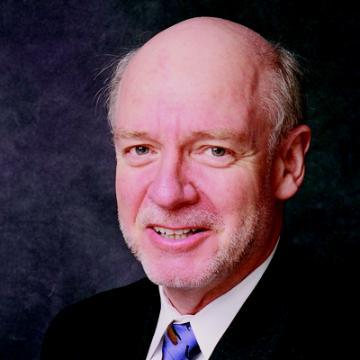 A person wearing a suit and tie smiling.