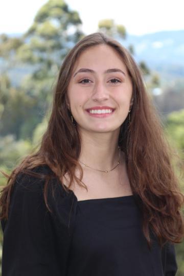 A smiling person named Natalia Rey with a nature background.