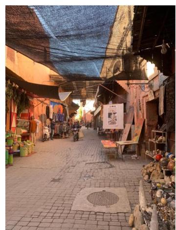 Bustling Marrakech street market scene with shoppers and various market stalls.