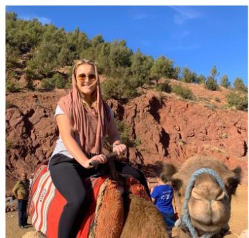 A person riding a camel outdoors under a clear blue sky.