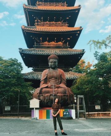 Person standing in front of a multi-tiered pagoda structure.