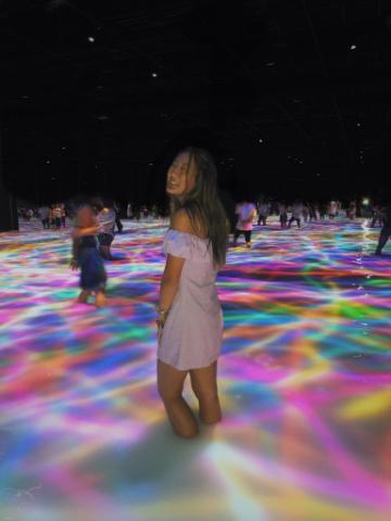 A person in a colorful, illuminated area with others in the background.