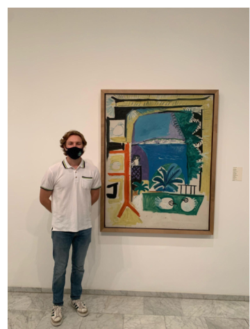 A person standing beside a framed artwork in a gallery.