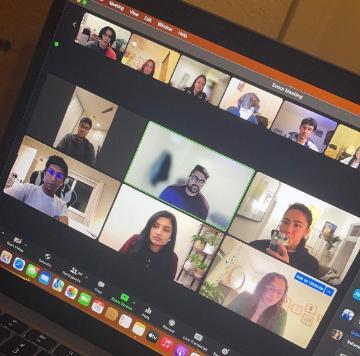 A laptop screen showing a video conference with multiple participants.