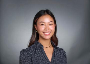 Portrait photo of Katie Eng smiling against a grey background.