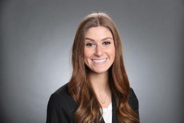 A person smiling against a plain gray background.