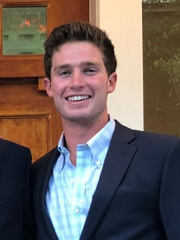 A smiling man in a suit and a light blue shirt.