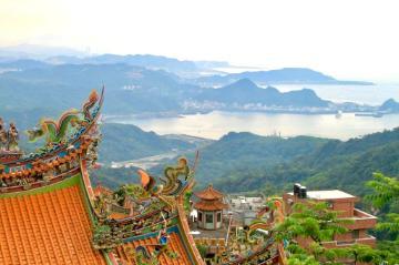 Mountainous landscape with terraced fields and traditional rooftops in the foreground.