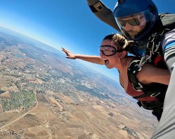 Two people skydiving, airborne with a clear view of the landscape below.