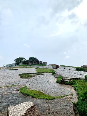 A rocky terrain with greenery and a cloudy sky.