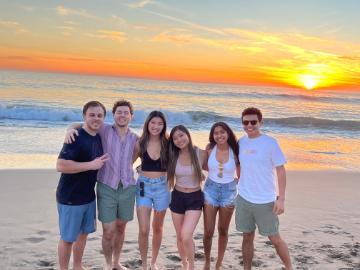 A group of friends posing on a beach at sunset.