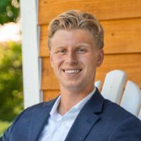 A person in a suit sitting on a porch chair.